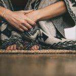 feet and hands of woman sitting on the floor wearing handmade poncho. copy space.